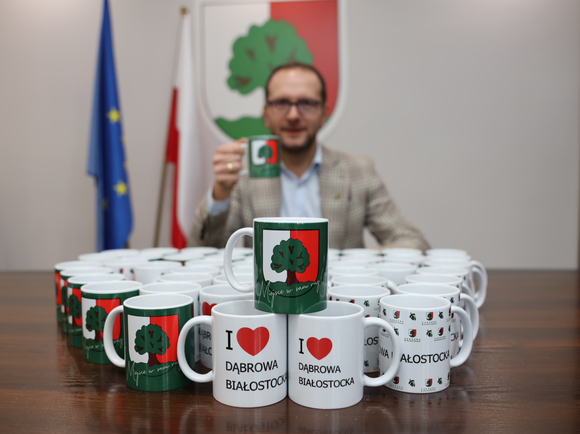 burmistrz pije kawę w kubku grafiką gminy