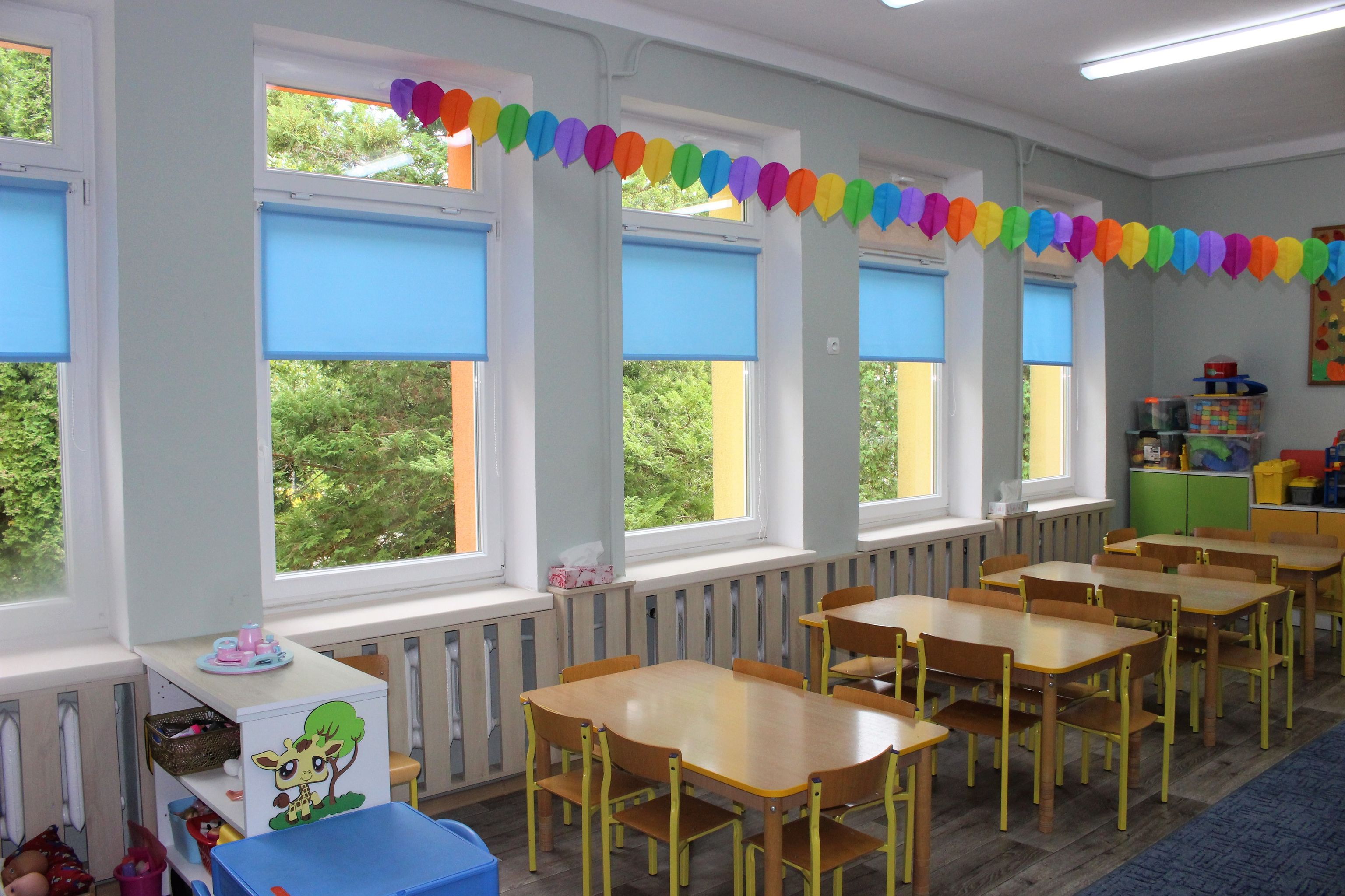 wyremontowana sala w przedszkolu, girlanda zawieszona nad stolikami dla dzieci